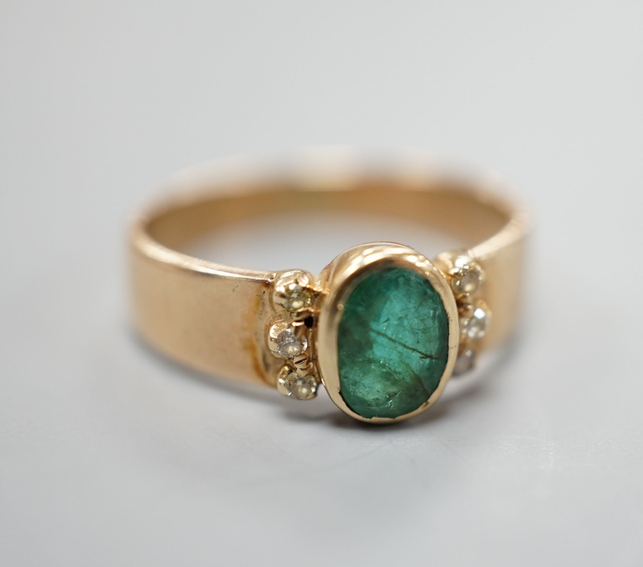 A yellow metal, oval cut emerald and six stone diamond chip set ring, size O, gross weight 3 grams.